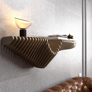 Pode incluir: Uma prateleira de parede de madeira com um design &uacute;nico em forma de onda. A prateleira est&aacute; montada em uma parede cinza e tem uma pequena l&acirc;mpada e livros no topo.