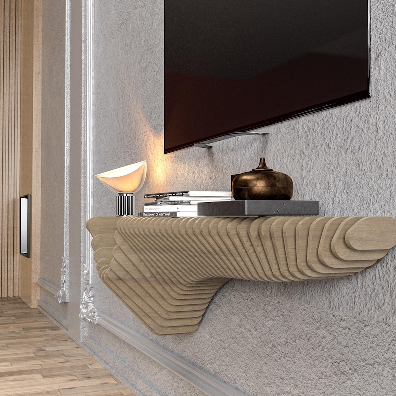 Pode incluir: Uma prateleira de parede de madeira com um design &uacute;nico em forma de onda. A prateleira &eacute; montada em uma parede e tem uma superf&iacute;cie plana para exibir objetos. H&aacute; livros, uma l&acirc;mpada e um objeto decorativo na prateleira.