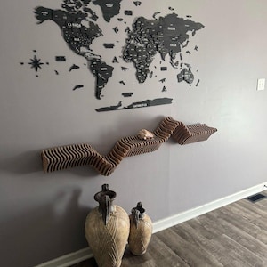 以下が含まれることがあります： 「Heaven and Earth are full of His Glory」という文字が書かれた黒い木製の地球儀。グレーの壁に掛けられており、その下に木製の棚がある。棚の前に、床に2つの装飾的な陶器の壺が置かれている。