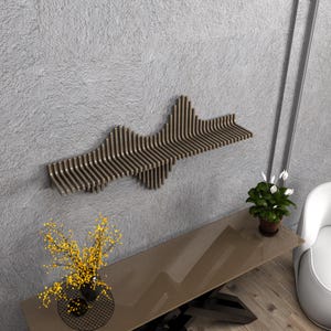 Op de afbeelding: Een bruine houten wandplank met een uniek golvend ontwerp. De plank is gemonteerd op een grijze muur en heeft een moderne, minimalistische esthetiek.
