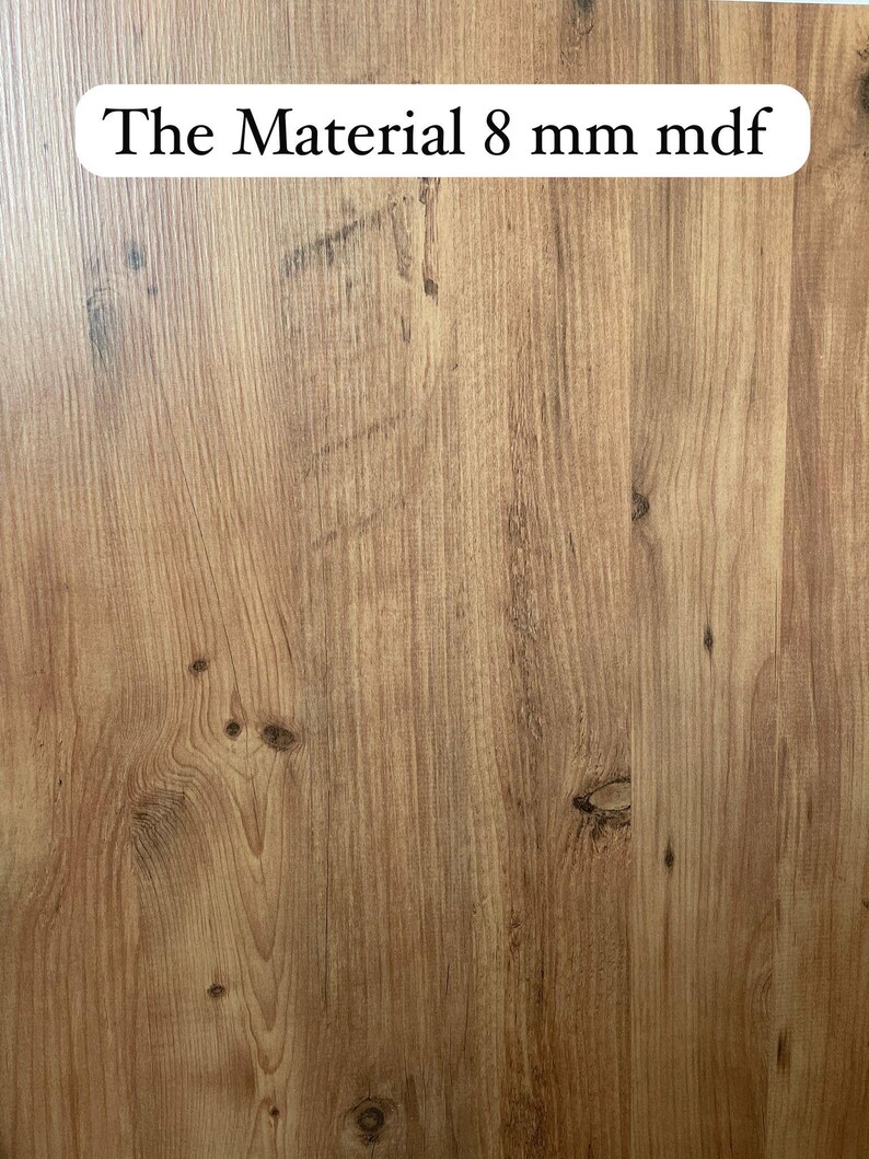 Pode incluir: Close-up de uma superf&iacute;cie de gr&atilde;o de madeira com o texto "The Material 8 mm mdf" impresso em um adesivo oval branco.