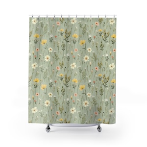 May include: A shower curtain featuring a repeating pattern of wildflowers in yellow, white, and pink against a muted green background. The floral design includes various types of flowers and foliage, creating a natural and whimsical aesthetic.