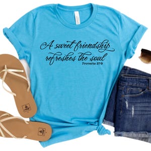 May include: A turquoise blue t-shirt with a black graphic that reads "A sweet friendship refreshes the soul" with the scripture reference "Proverbs 27:9" underneath.