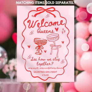 May include: A pink sign with red text and illustrations. The sign reads "Welcome Queens" and "See how we slay together?" with images of champagne glasses. The sign is for a Galentine's Girls Night event.