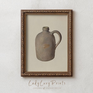 May include: Framed print of a vintage stoneware jug in shades of gray and brown. The jug has a handle and a small opening at the top. The frame is a dark brown with an ornate design. The text "LadyLuxy Prints" is at the bottom.