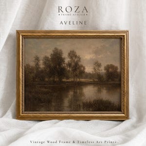 May include: A rectangular landscape art print featuring a dark, moody scene of trees reflected in a calm body of water, encased in a metallic gold frame with a beaded inner edge. The text ROZA FRAME ATELIER AVELINE appears above the frame.