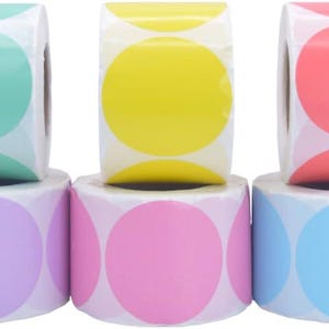 Op de afbeelding: Een verzameling kleurrijke, ronde stickers in verschillende tinten, waaronder groen, geel, rood, paars, roze en blauw. De stickers zijn gerangschikt in rollen, waarbij elke rol een andere kleur weergeeft. Deze stickers zijn geschikt voor knutselen en organisatie.