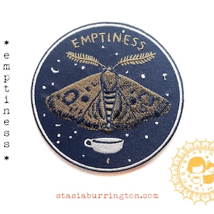 May include: Embroidered iron-on patch with a navy blue background. The patch features a moth design in shades of brown and gold, with the word "EMPTINESS" arched above. A small teacup is at the bottom. The text "stasiaburrington.com" is also visible.