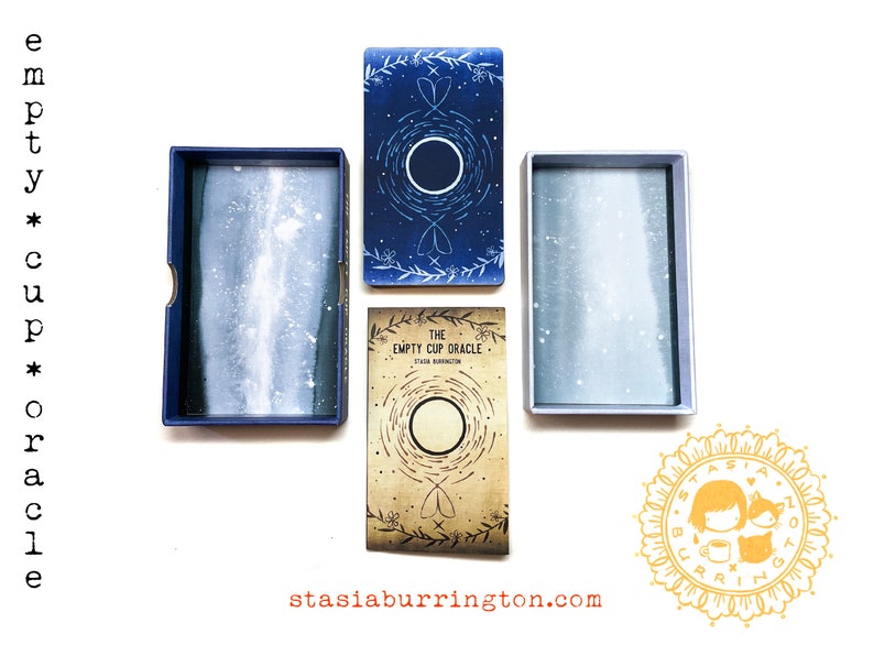 May include: An overhead shot of an oracle card set. The set includes a box with the words "empty cup oracle" on the side, and the text "THE EMPTY CUP ORACLE" on the front of the card box. The cards and boxes are blue and beige.