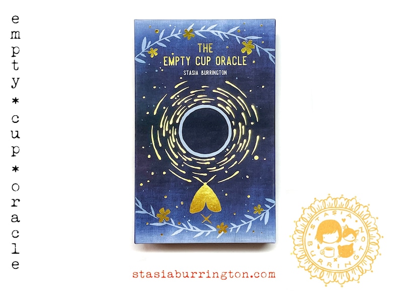 May include: A deck of oracle cards titled "The Empty Cup Oracle" by Stasia Burrington. The card box features a dark blue background with a gold and white design of a circle, stars, and a moth. The website stasiaburrington.com is also visible.