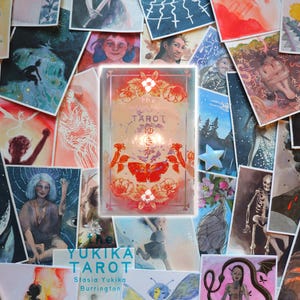 May include: A rectangular tarot card deck box featuring a central red moth illustration, floral motifs, and the text "the TAROT" with Japanese characters. The box is surrounded by a collage of various artistic prints depicting figures, nature, and skulls.