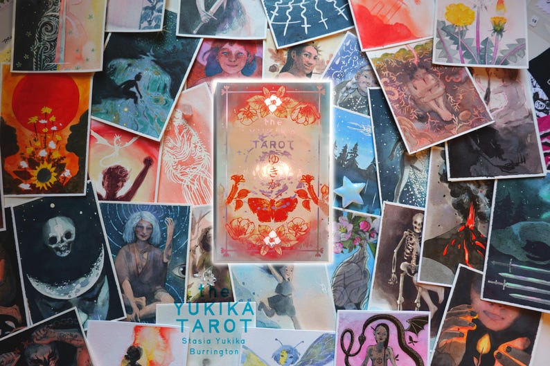 May include: A rectangular tarot card deck box featuring a central red moth illustration, floral motifs, and the text "the TAROT" with Japanese characters. The box is surrounded by a collage of various artistic prints depicting figures, nature, and skulls.