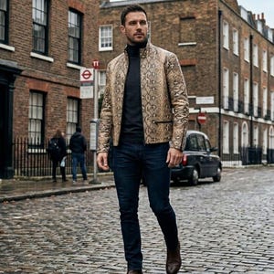 May include: A man wearing a snakeskin-patterned jacket, black turtleneck, and dark blue jeans walks down a cobblestone street. The jacket is tan and brown with a subtle sheen. Brown leather boots complete the outfit. The background features brick buildings and a red telephone booth.