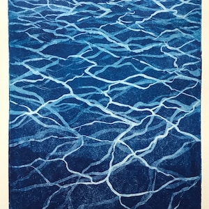 May include: An abstract print of water in blue and white with a white signature in the bottom right corner and the number "14/5" in the bottom left corner.