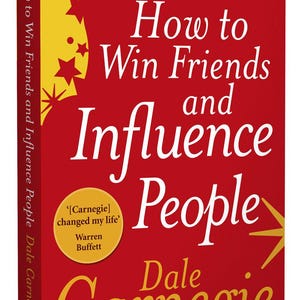 May include: A red book with the title "How to Win Friends and Influence People" by Dale Carnegie. The book cover features a yellow starburst design and a quote from Warren Buffett: "[Carnegie] changed my life."