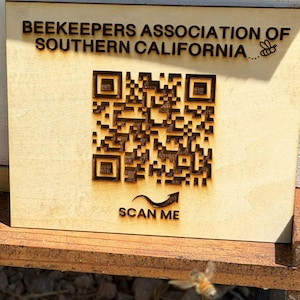 May include: A rectangular light-colored wooden sign featuring the laser-engraved text BEEKEEPERS ASSOCIATION OF SOUTHERN CALIFORNIA, a small bee icon, a large central QR code, and the text SCAN ME with an upward-pointing arrow graphic.