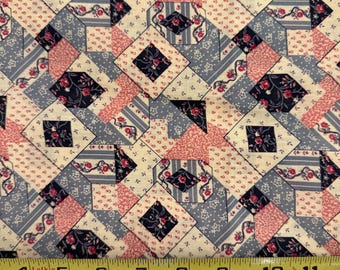 May include: Close-up of a patchwork fabric with a repeating pattern. The design features squares and diamond shapes in cream, light blue, pink, and navy blue. The fabric has floral and striped accents. A yellow measuring tape is across the bottom.