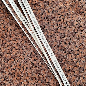 May include: Close-up of fabric with a repeating pattern of brown coffee beans on a black background. The fabric label reads "DEB STRAIN for moda modafabrics.com 100% cotton Pattern # 19124".