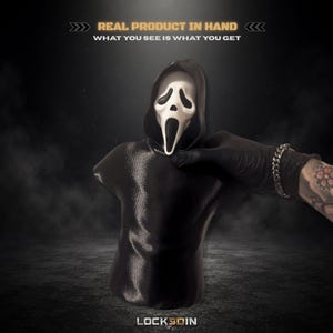 May include: A black hooded bust featuring a white ghost-like mask with hollow black eyes and an elongated open mouth. The text above reads REAL PRODUCT IN HAND WHAT YOU SEE IS WHAT YOU GET and the text below reads LOCK3DIN in white lettering.