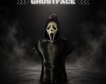Può includere: Un busto di Ghostface che presenta l'iconica maschera bianca con aperture nere per gli occhi e la bocca, attaccata a una veste nera con cappuccio. Il testo GHOSTFACE appare in alto e il testo LOCK3DIN è posizionato in basso sul display scuro.