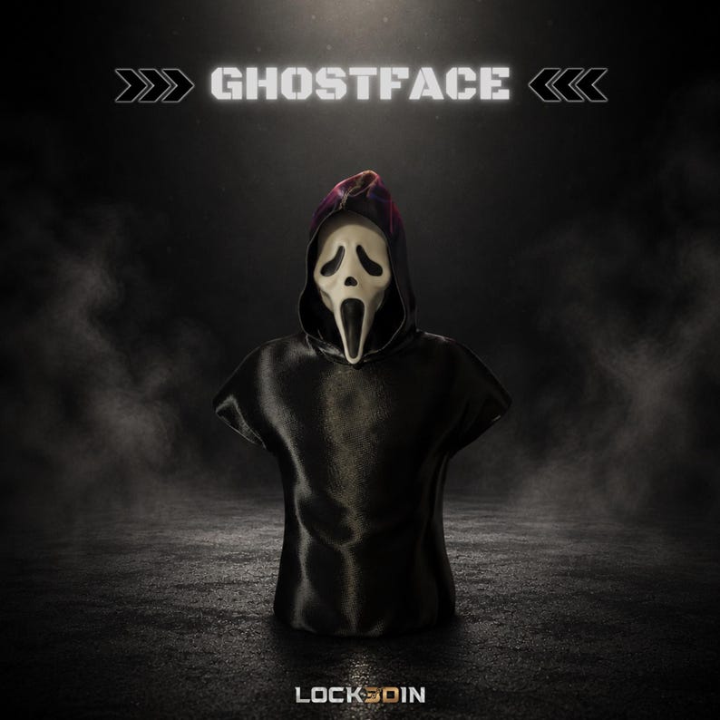 May include: A Ghostface bust featuring the iconic white mask with black eye and mouth openings, attached to a black hooded robe. The text GHOSTFACE appears at the top, and the text LOCK3DIN is positioned at the bottom of the dark, smoky display.
