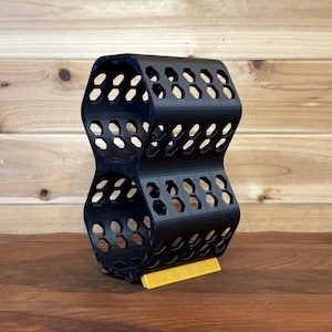 May include: Black honeycomb wine rack with a yellow base. The rack is designed to hold two bottles of wine.