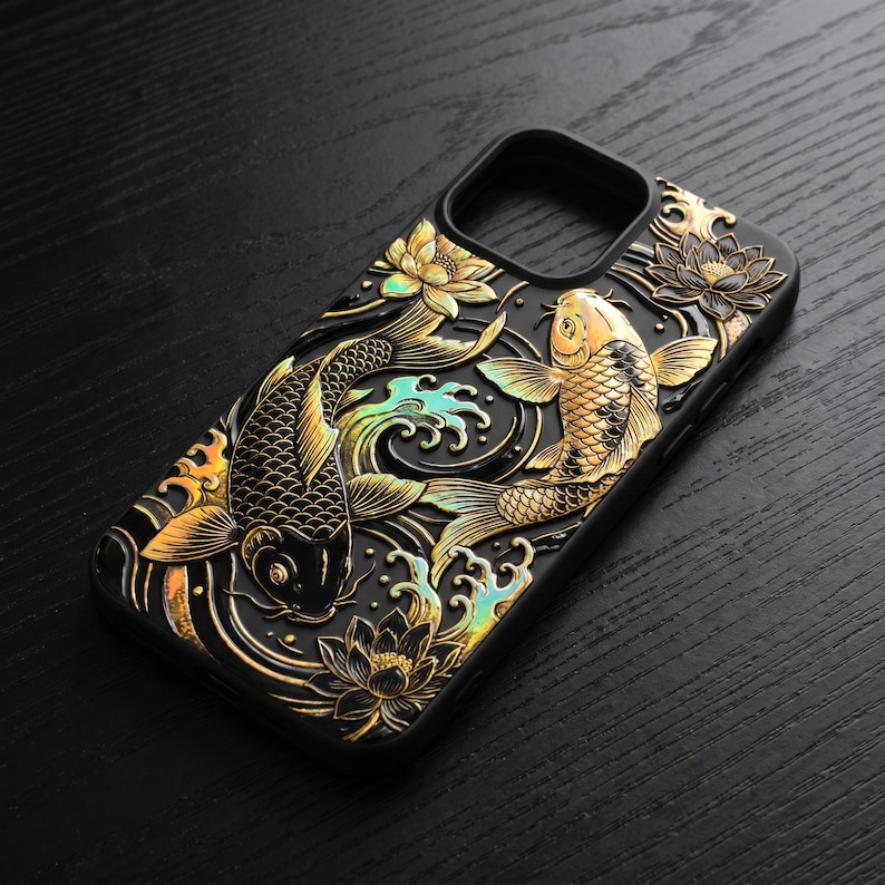 May include: A black phone case featuring a raised, three-dimensional relief design of two koi fish swimming among stylized water waves and lotus flowers. The fish and floral elements are finished in a metallic gold with iridescent accents.