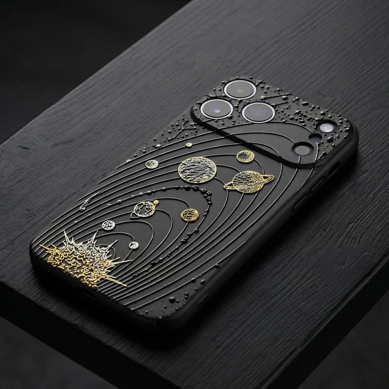 Peut inclure: Coque de t&eacute;l&eacute;phone noire avec un motif d&eacute;taill&eacute; du syst&egrave;me solaire en or et argent. La coque pr&eacute;sente une surface textur&eacute;e avec des plan&egrave;tes et des trajectoires orbitales en relief. Le design comprend un &eacute;clat solaire en bas.