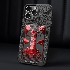 May include: Black phone case with a red and black tarot card design. The card is The Tower, with the number XVI. The case has a raised design and a glossy finish.