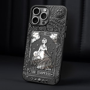 K&ouml;nnte beinhalten: Schwarze Handyh&uuml;lle mit detailliertem Pr&auml;gedesign. Die H&uuml;lle zeigt eine silberne Tarotkartenillustration von "The Empress", umgeben von komplizierten Mustern und Symbolen. Die H&uuml;lle hat ein mattes Finish.