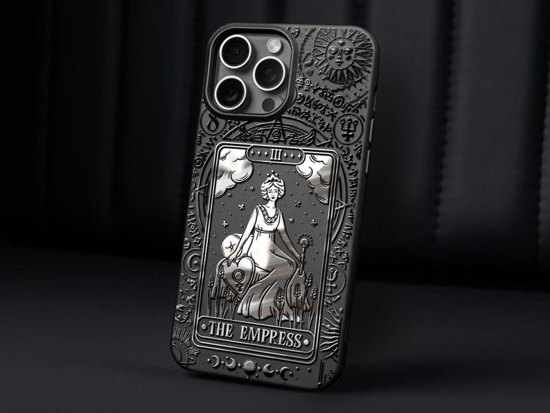 K&ouml;nnte beinhalten: Schwarze Handyh&uuml;lle mit detailliertem Pr&auml;gedesign. Die H&uuml;lle zeigt eine silberne Tarotkartenillustration von "The Empress", umgeben von komplizierten Mustern und Symbolen. Die H&uuml;lle hat ein mattes Finish.