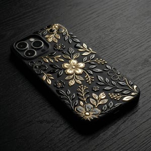 Puede incluir: Funda de tel&eacute;fono negra con dise&ntilde;o floral. La funda presenta flores y hojas en relieve doradas y negras, creando un efecto tridimensional. Acabado brillante y abertura para la c&aacute;mara.