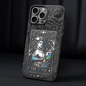 K&ouml;nnte beinhalten: Schwarze Handyh&uuml;lle mit detailliertem, graviertem Design. Die H&uuml;lle zeigt eine Tarotkarten-Illustration einer Krankenschwester mit Klemmbrett und dem Text "THE NURSE". Die H&uuml;lle hat ein Sonnen- und Mond-Design.