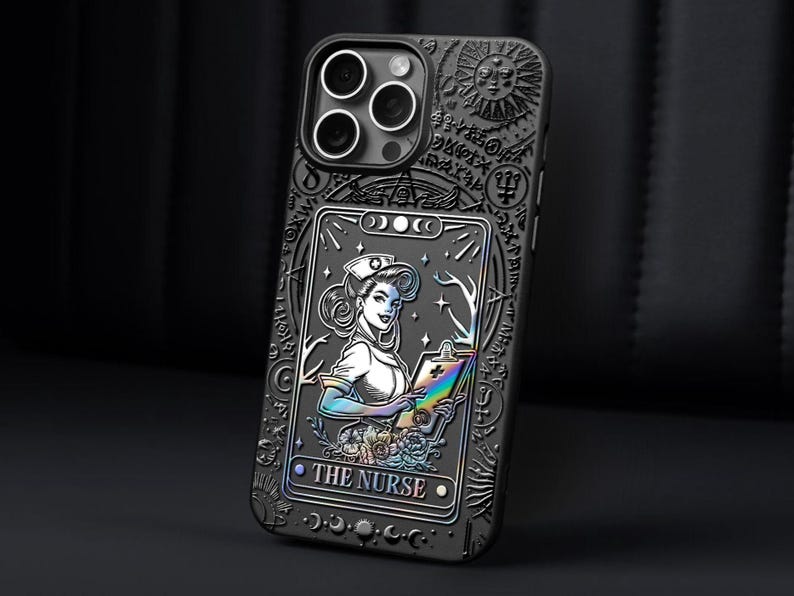 K&ouml;nnte beinhalten: Schwarze Handyh&uuml;lle mit detailliertem, graviertem Design. Die H&uuml;lle zeigt eine Tarotkarten-Illustration einer Krankenschwester mit Klemmbrett und dem Text "THE NURSE". Die H&uuml;lle hat ein Sonnen- und Mond-Design.