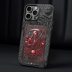 K&ouml;nnte beinhalten: Schwarze Handyh&uuml;lle mit einem rot-schwarzen gepr&auml;gten Design, das eine Tarotkarte des Sensenmanns zeigt. Die H&uuml;lle hat eine detaillierte, gotische &Auml;sthetik mit Rosen, Totenk&ouml;pfen und dem Wort "DEATH".