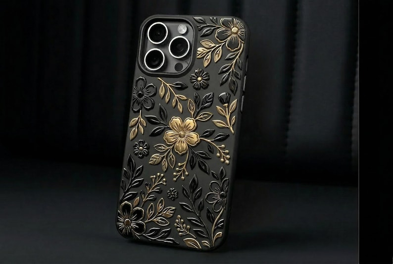Puede incluir: Funda de tel&eacute;fono negra con dise&ntilde;o floral. La funda presenta flores y hojas en relieve en dorado y negro. La funda tiene un acabado brillante y est&aacute; dise&ntilde;ada para un tel&eacute;fono inteligente.