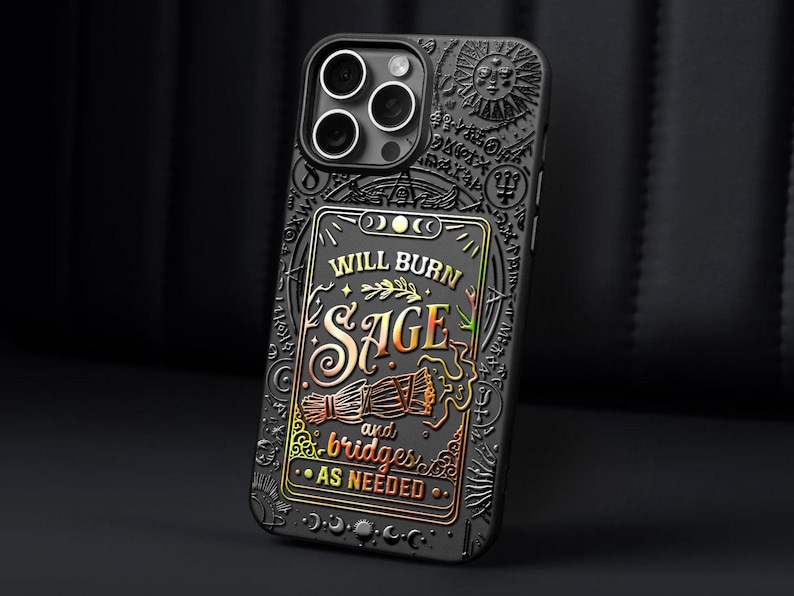 K&ouml;nnte beinhalten: Schwarze Handyh&uuml;lle mit detailliertem, gepr&auml;gtem Design. Die H&uuml;lle zeigt den Text "WILL BURN SAGE and bridges AS NEEDED" in Gold und Orange, mit zus&auml;tzlichen Symbolen und einem Sonnendesign. F&uuml;r ein Smartphone.