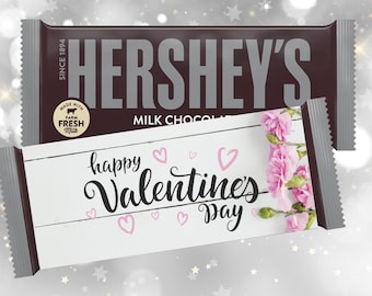 May include: Hershey's Milk Chocolate bar with a Valentine's Day themed wrapper. The wrapper features the text "happy Valentine's day" with pink hearts and flowers. The Hershey's bar is dark brown.