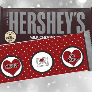 May include: A Hershey's Milk Chocolate bar with a red and white polka dot wrapper. The wrapper has three Valentine's Day themed circles with the text "XOXO", "Be Mine", and a white envelope with a red heart.