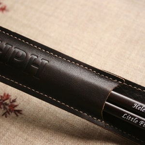 May include: A brown leather case with the initials "HPH" embossed on the front. The case contains two wooden chopsticks with the names "Helena" and "Little Fish" engraved on them.