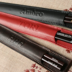 May include: Three leather chopsticks cases with personalized names. The cases are black, red, and brown. The chopsticks are visible inside the cases.