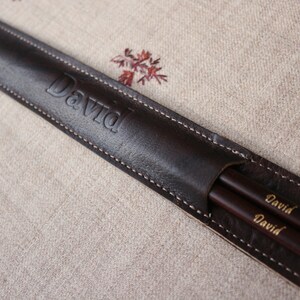 May include: A brown leather case with the name "David" embossed on the front. The case contains two wooden chopsticks with the name "David" engraved on them.
