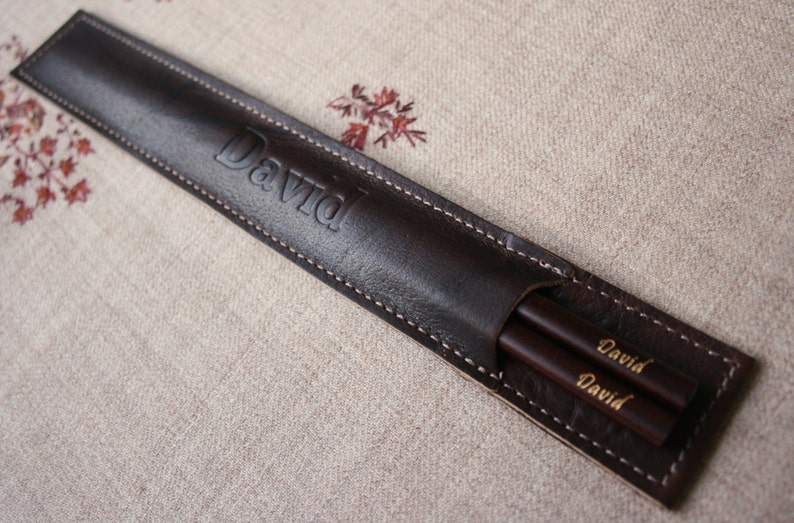 May include: A brown leather case with the name "David" embossed on the front. The case contains two wooden chopsticks with the name "David" engraved on them.
