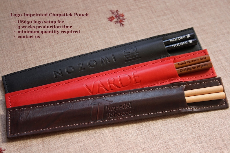 May include: Three leather chopsticks pouches with different logos. The top pouch is black with the word "NOZOMI" embossed in white. The middle pouch is red with the word "VARDE" embossed in white. The bottom pouch is brown with the words "Imperial Tobacco" embossed in white.