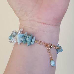 Puede incluir: Una pulsera dorada con fragmentos irregulares de piedras preciosas azul claro y acentos de perlas blancas. La pulsera se asegura con un cierre de mosquet&oacute;n y una cadena ajustable. Las piedras preciosas miden aproximadamente 1,3 cm de largo.