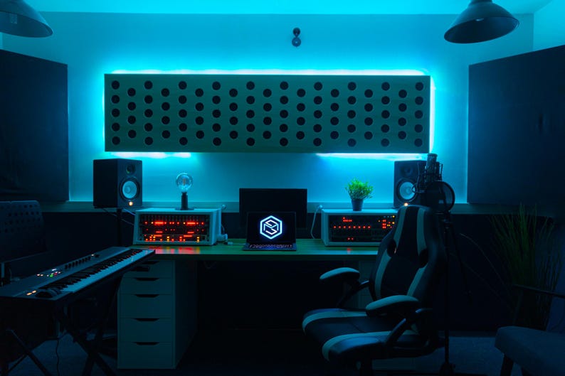 May include: A home recording studio with a blue and white color scheme. The studio features a computer, a keyboard, a microphone, and a chair. The walls are lined with sound-absorbing panels.