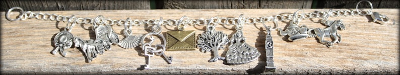 May include: A silver charm bracelet with various charms, including a key, a tree, a house, a letter, and a horse. The charms are attached to a silver chain.