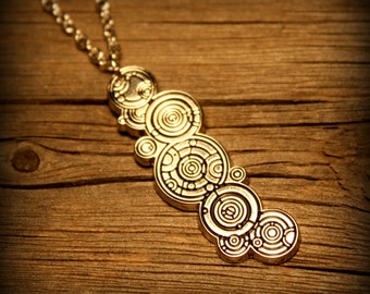May include: A gold necklace with a pendant featuring a series of concentric circles, reminiscent of a futuristic design.