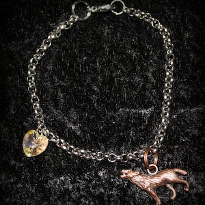 May include: A silver chain bracelet with a copper wolf charm and a clear heart-shaped charm.