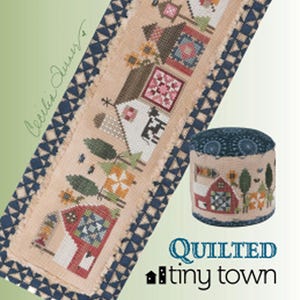 May include: A quilted needlepoint design featuring a tiny town scene with houses, trees, and flowers. The design is framed with a blue and white border. A matching round pincushion is also shown. The text "QUILTED tiny town" is visible.